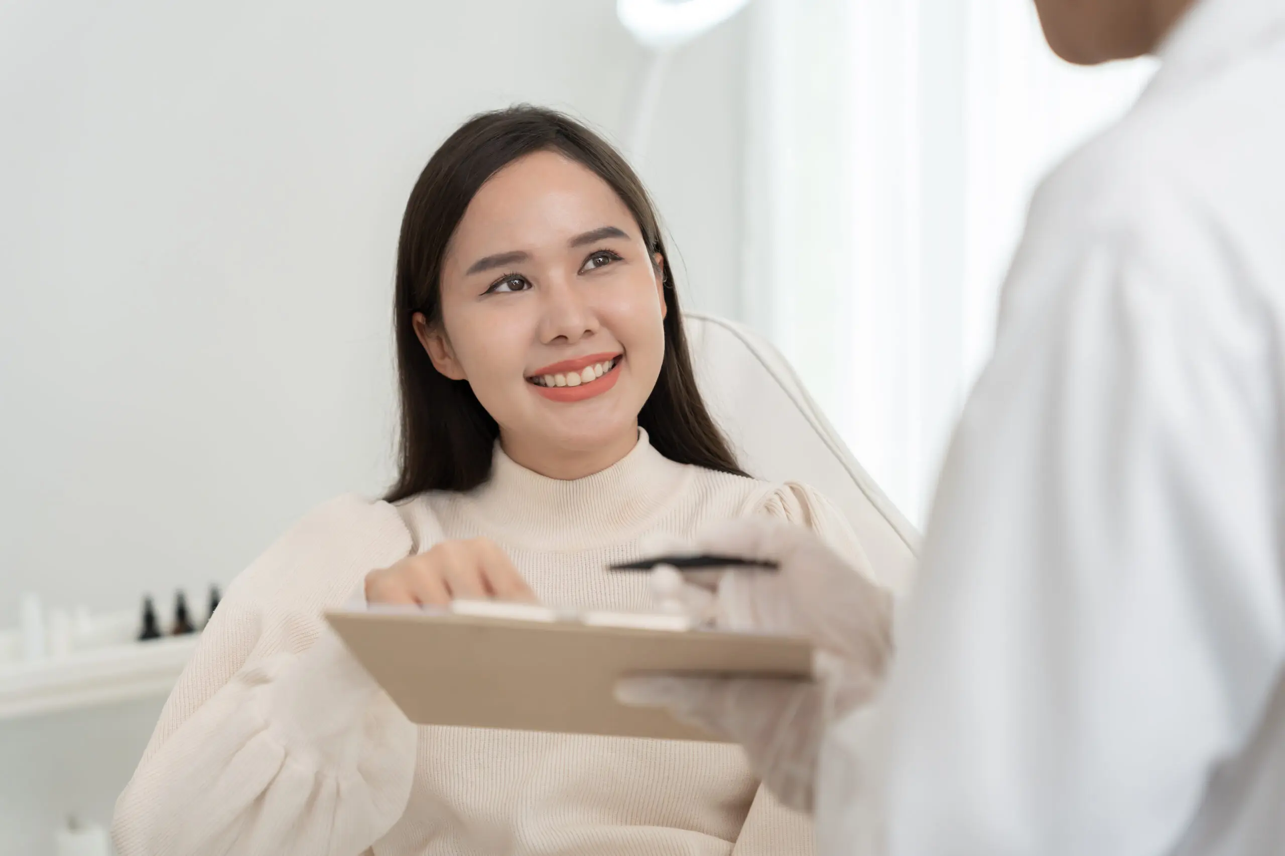 Smiling patient consulting doctor with clipboard
