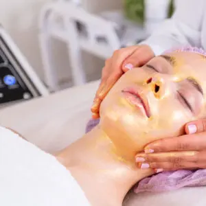 Woman receiving gold facial treatment at spa
