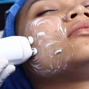 Woman receiving ultrasonic facial cleansing treatment